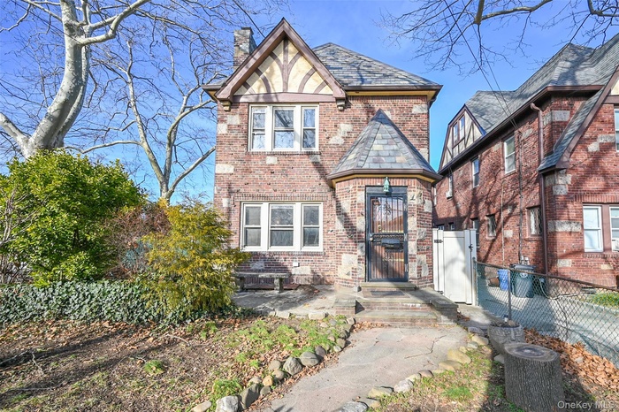 English style home with brick siding, a chimney, and a patio