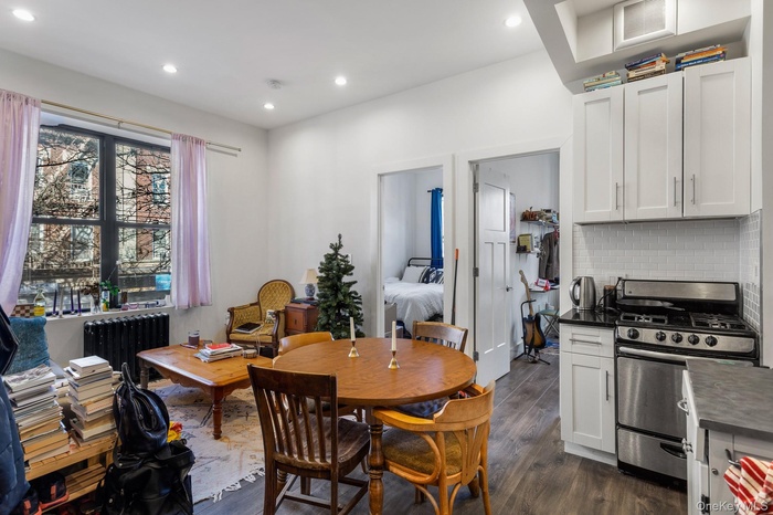 Dining space featuring dark wood-style floors, radiator heating unit, and recessed lighting