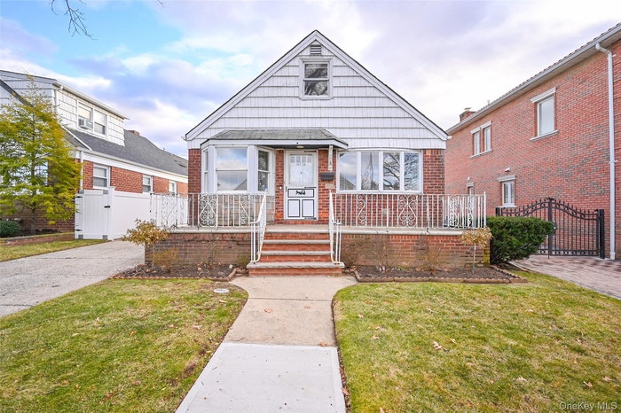 Bungalow-style home featuring brick siding, a gate, and a front lawn