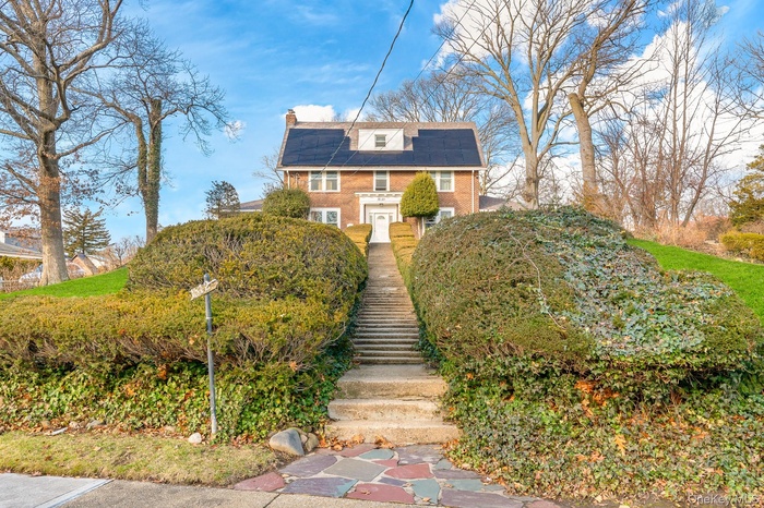 View of front facade featuring solar panels and a chimney