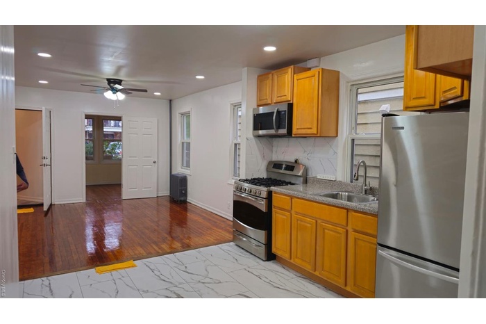 Kitchen with refrigerator, range, light wood-style flooring, stainless steel microwave, and decorative backsplash