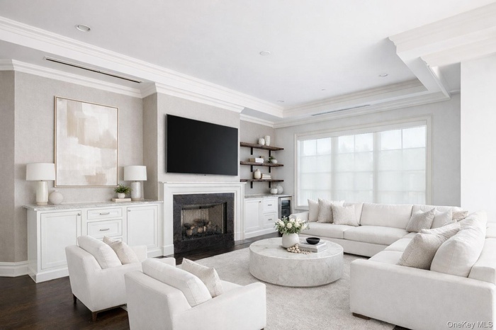 Living room with ornamental molding, a fireplace, and dark wood-style flooring