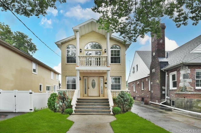 View of front facade featuring a balcony, brick siding, and a gate