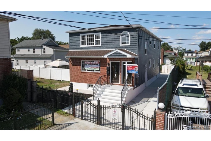 View of front of house with a gate, a fenced front yard, brick siding, and a shingled roof