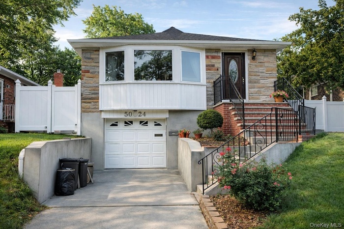 View of front facade featuring stone siding, an attached garage, and driveway