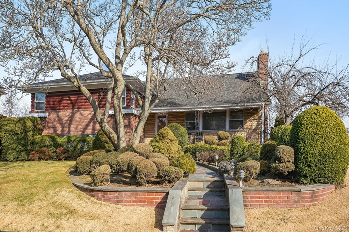 View of front of house with a front lawn and roof with shingles