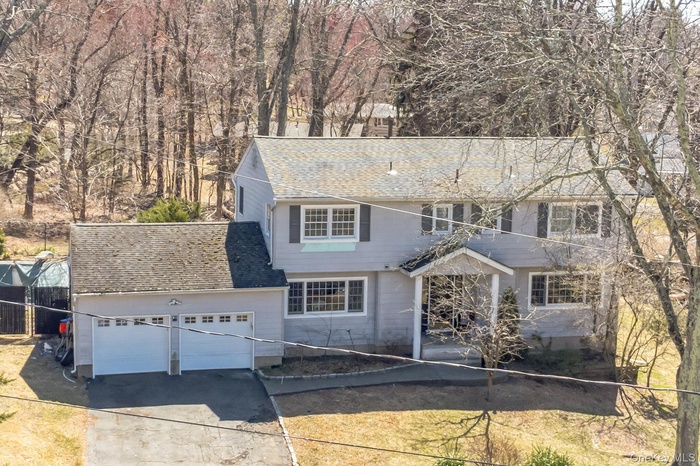 View of front facade with concrete driveway, a garage, and a shingled roof
