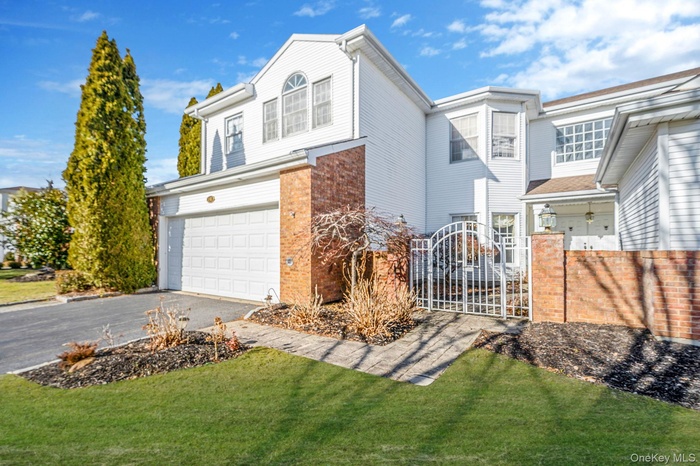 Traditional home with a gate, driveway, a garage, and brick siding
