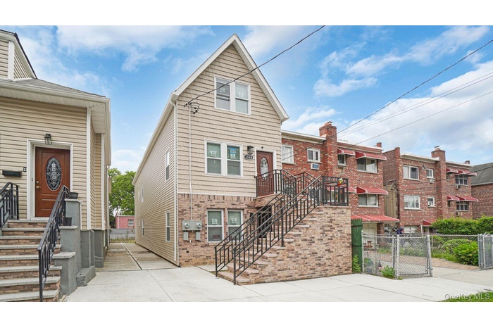 View of front facade featuring a gate, stairs, and brick siding