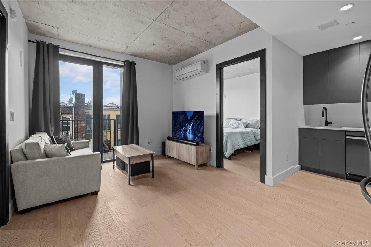 Living room with light wood-style floors and a wall mounted air conditioner