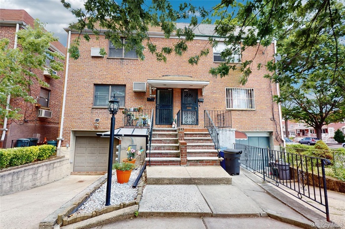 View of front of property featuring a garage, brick siding, and driveway
