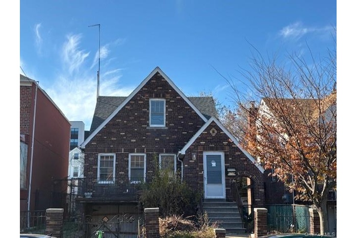 Tudor home featuring brick siding and roof with shingles