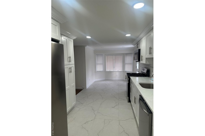 Kitchen featuring stove, light stone counters, refrigerator, light marble finish flooring, and dishwashing machine