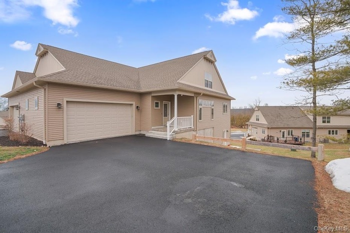 View of front facade featuring driveway, a porch, a garage, and a shingled roof