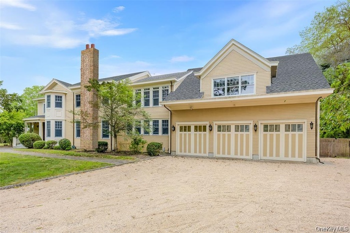 View of front of house featuring dirt driveway, a chimney, a shingled roof, and an attached garage