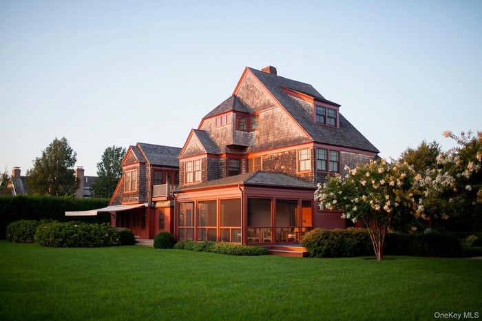 Back of property featuring a sunroom, a lawn, and a chimney
