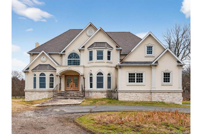 View of front of house with french doors, stucco siding, stone siding, and a chimney