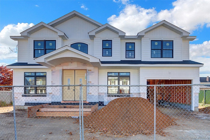 View of front of house with an attached garage, a fenced front yard, a gate, and driveway