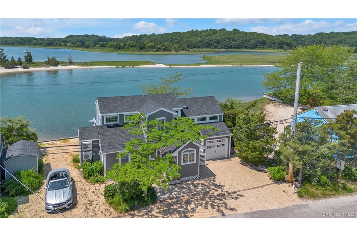 Aerial view of property and surrounding area featuring a heavily wooded area and a nearby body of water