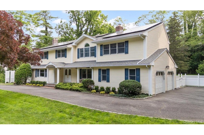 View of front of property featuring solar panels, a garage, a chimney, and covered porch