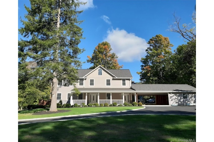 View of front facade featuring covered porch, a front lawn, and a carport