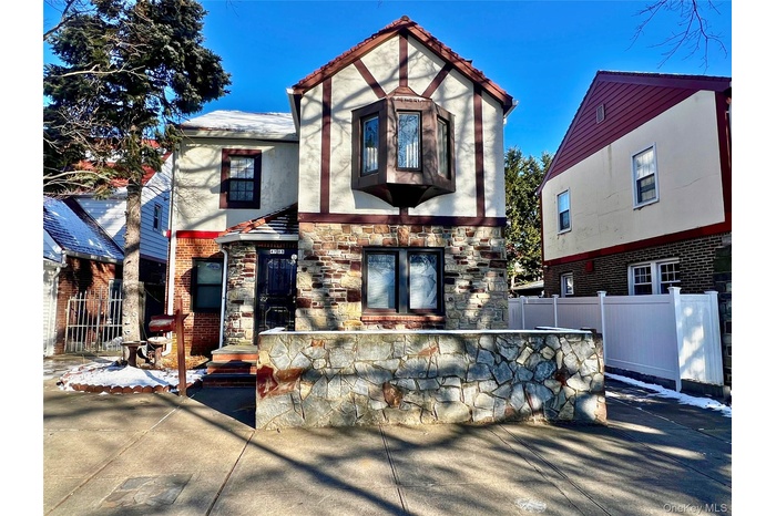 View of front of property featuring a patio, brick siding, stone siding, and stucco siding