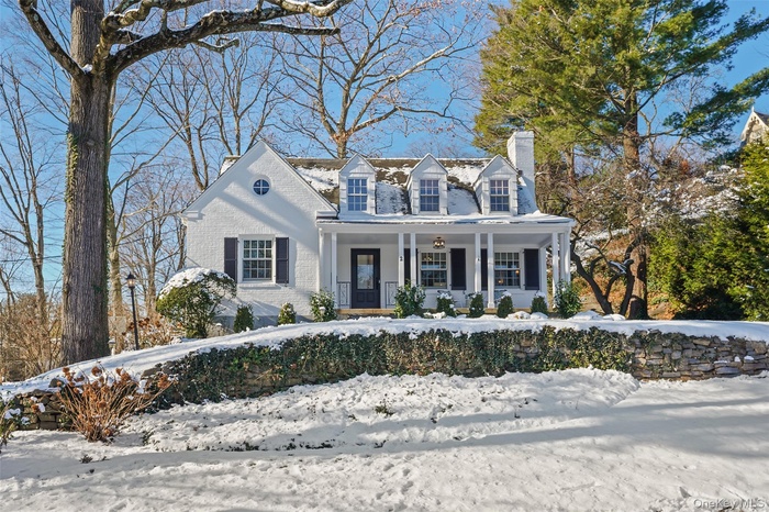 New england style home with covered rocking chair porch and brick siding