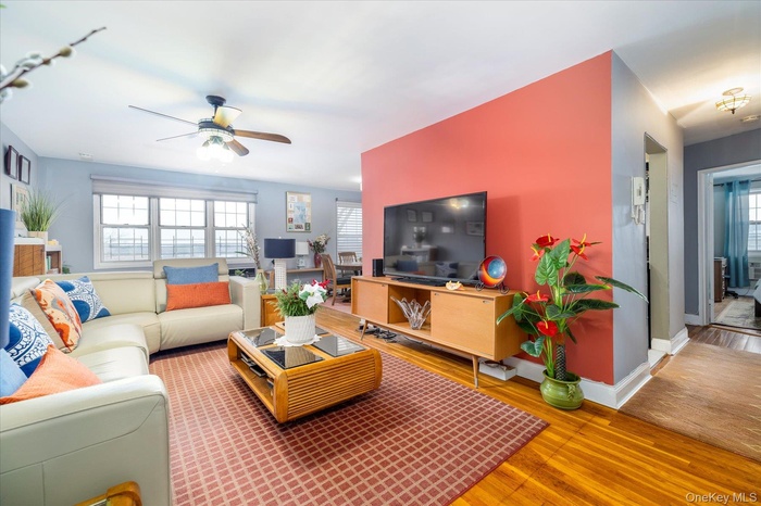 Living room with plenty of natural light, wood finished floors, and ceiling fan