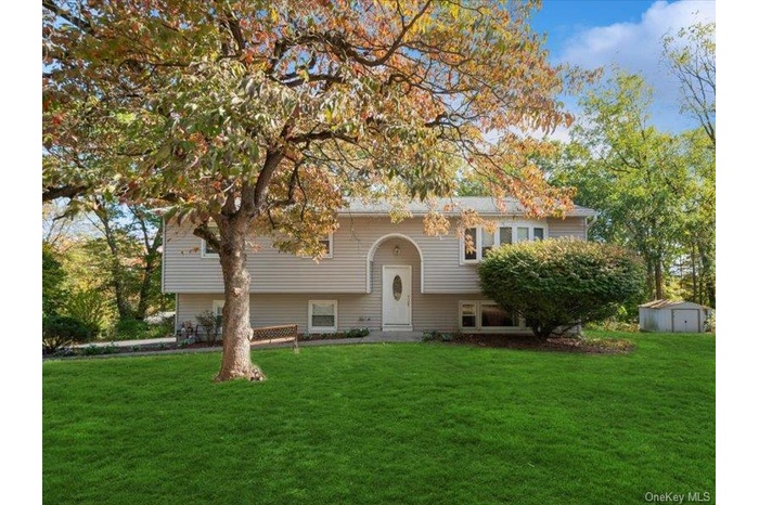 Bi-level home with a front yard and a storage shed