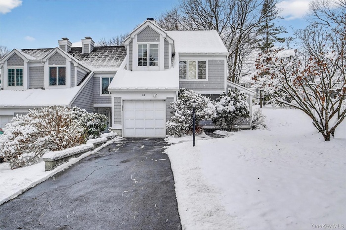 View of front facade with an attached garage, a chimney, and asphalt driveway