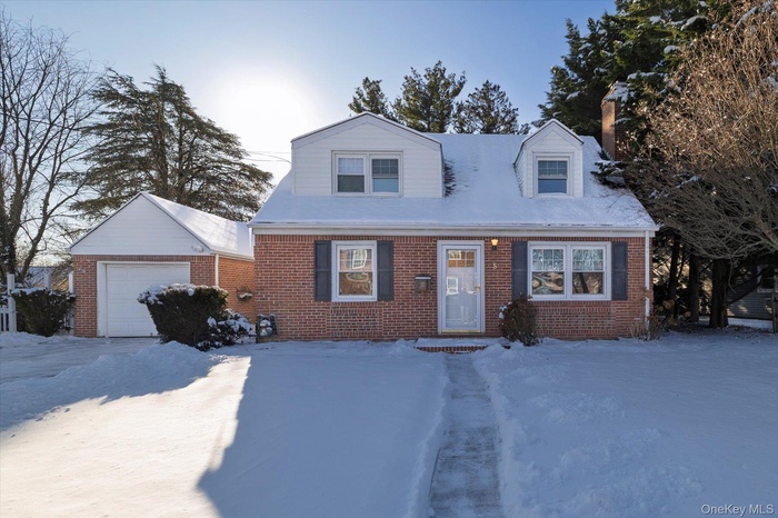 New england style home featuring brick siding and a garage