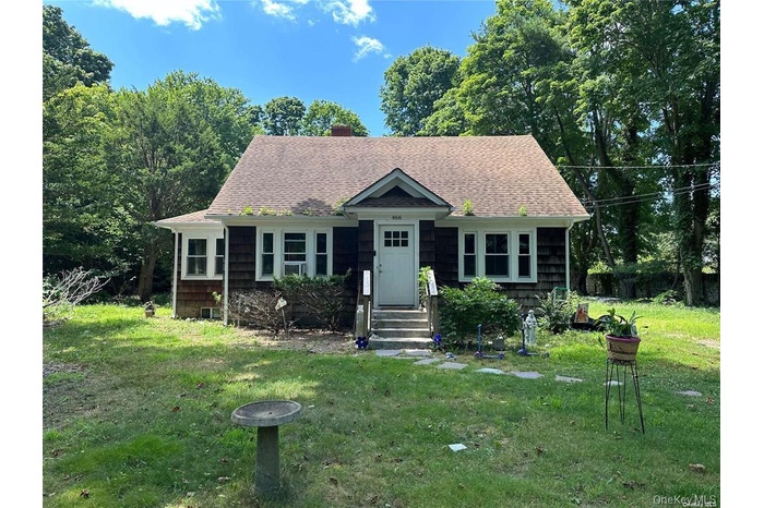 View of front of home featuring a front yard, a chimney, and a shingled roof