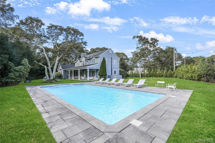 Outdoor pool featuring a lawn, a patio, and view of wooded area