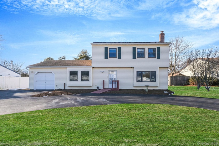 Colonial inspired home featuring a chimney and asphalt driveway