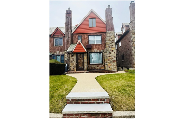 View of front facade with a chimney, stone siding, and a front yard