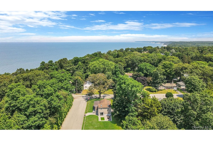 Drone / aerial view of a heavily wooded area and a nearby body of water