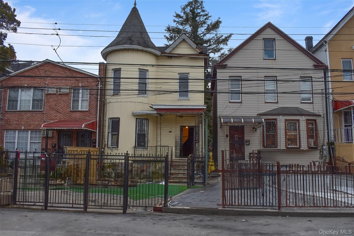 View of front of Victorian style home  with iron fenced front yard and a gate.