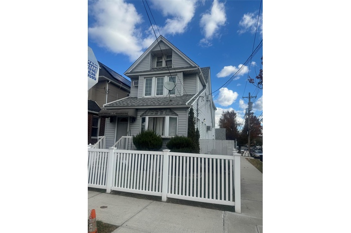 View of front of home featuring covered porch, a fenced front yard, and roof with shingles