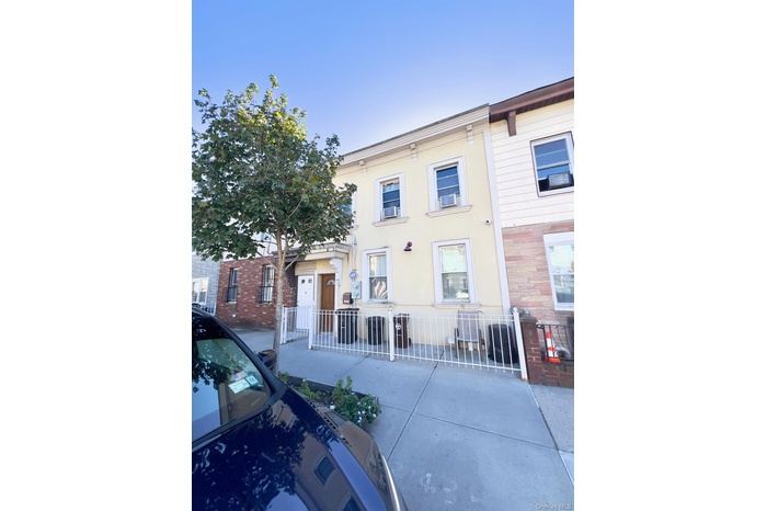 Italianate house featuring a fenced front yard, stucco siding, and a patio area