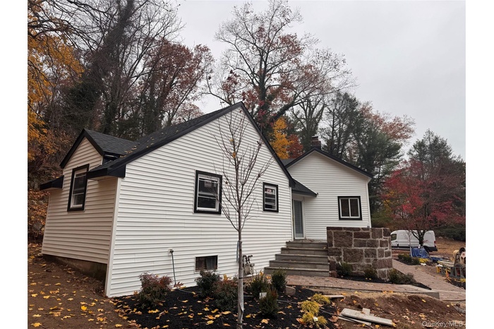 Rear view of house with roof with shingles and view of wooded area
