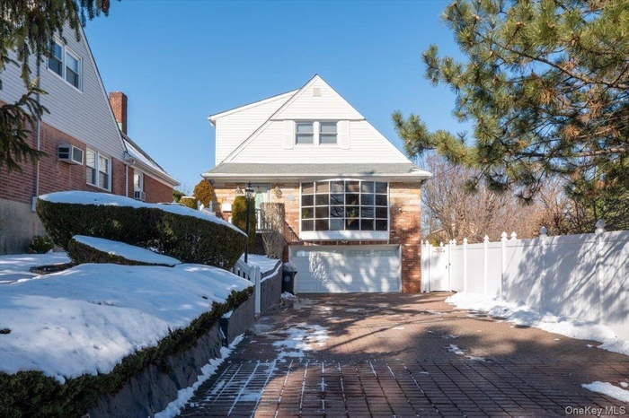 View of front of home featuring a garage, brick siding, and decorative driveway