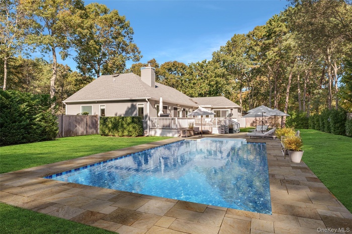 View of swimming pool featuring a wooden deck, a yard, and a patio area