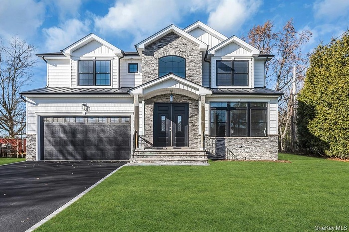 Craftsman-style  with a Colonial seam roof, stone siding, an attached garage, and board and batten siding
