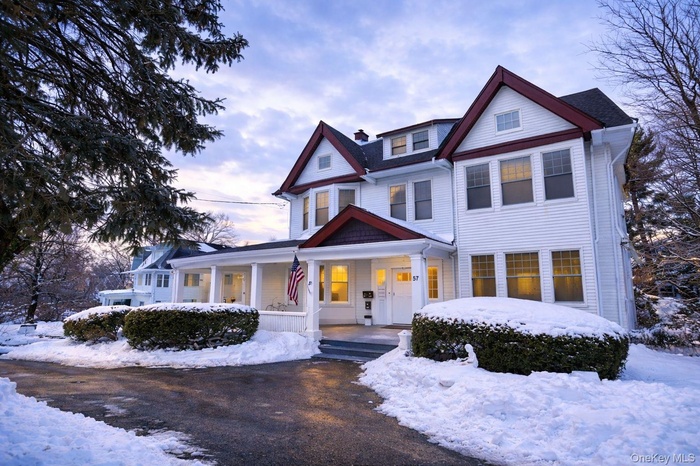 View of front of property featuring covered porch, a shingled roof, and a chimney.