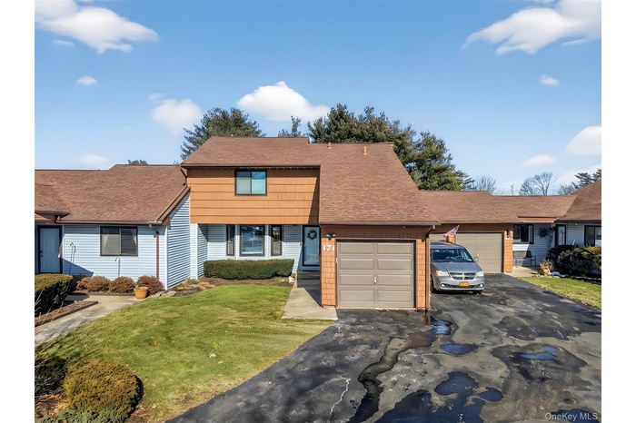 View of front of home featuring a front yard, roof with shingles, driveway, and a garage