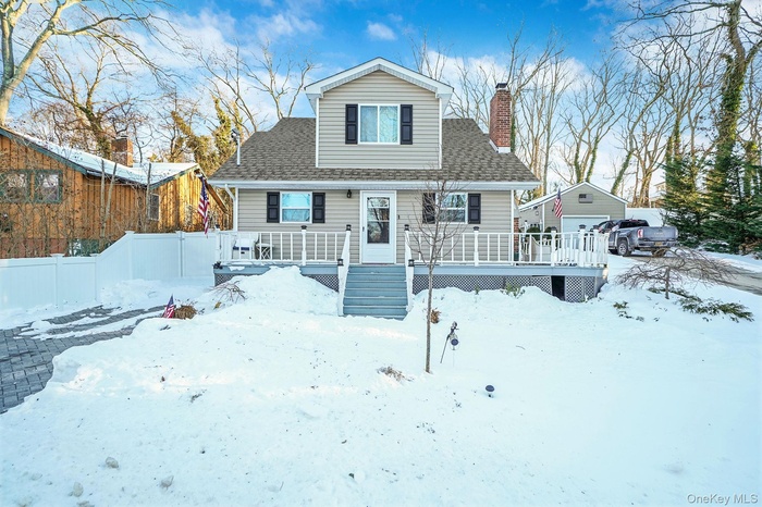 View of front of property featuring a deck, a chimney, roof with shingles, and a detached garage