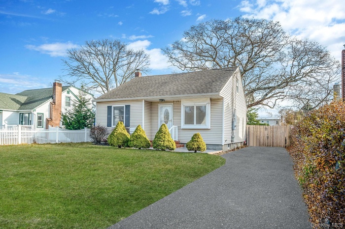 Bungalow-style house with a shingled roof, a chimney, and driveway