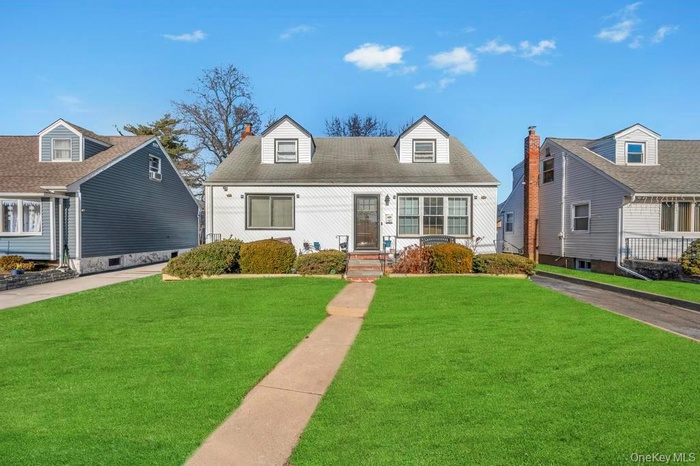 Cape cod home with a front lawn and a chimney