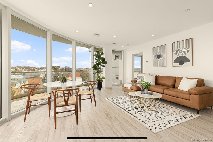 Living area with a wall of windows, recessed lighting, and light wood-style flooring