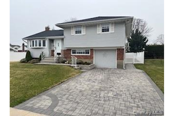 Tri-level home with a front lawn, fence, and driveway